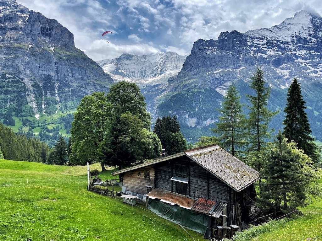 Photo looking over Grindelwald, Switzerland as a paraglider makes their descent 